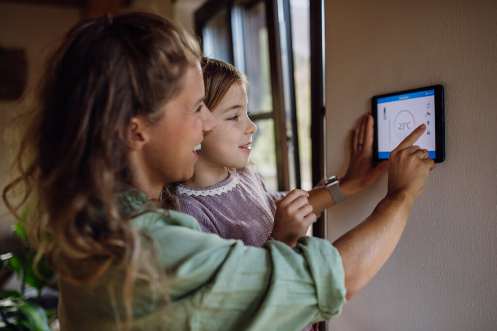 Girl helping mother to adjust thermostat
